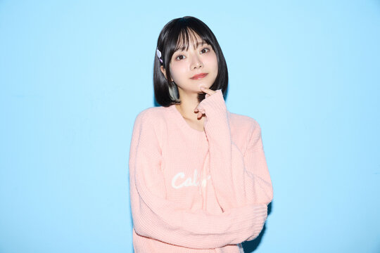 ブルー背景でキュートなポーズをする若い女性のポートレート