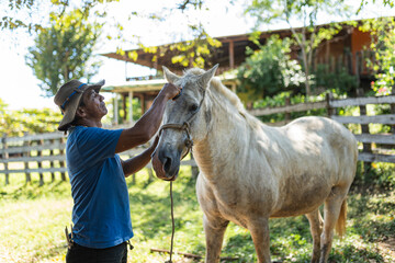 Fototapeta premium Costa Rican cowboy grooming white horse mane at traditional ranch