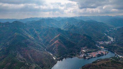 Autumn red leaves blanket the mountains, creating a continuous layer of forest colors. The aerial view reveals a continuous range of layered mountain scenery