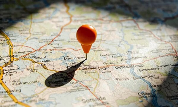 Orange map pin marking a location on a detailed paper map with roads