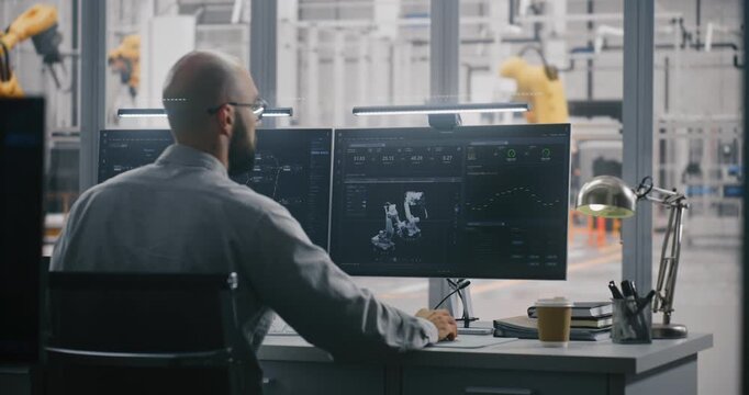 Two Professionals Working in Modern Industrial Control Room, With One Engineer Focused on Dual Monitors Displaying Automation Metrics. Data Analysis, and Robotics Management in Smart Manufacturing.
