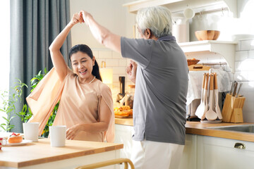 Asia happy older senior elderly couple dance waltz after cooking at kitchen room.&nbsp; Retirement couple embraces beloved celebrating Anniversary at home.&nbsp; Family Concept