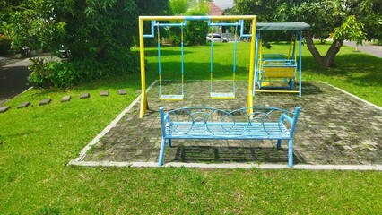 Sunny Outdoor Playground with Swings and Bench in a Peaceful Garden