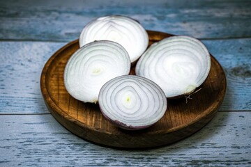 Freshly cut red onions with exposed papery outer layers arranged on a rustic wooden plate, showcasing culinary ingredients