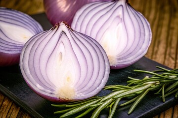 Vibrant purple onion halves revealing intricate layers and fresh rosemary sprigs on a dark surface, perfect for culinary inspiration.