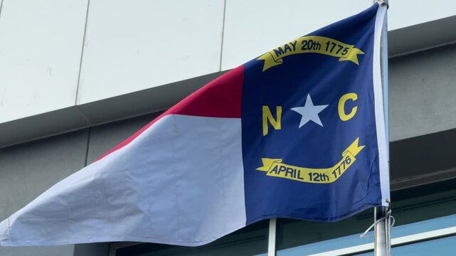 DOLLY SHOT - North Carolina State flag waving in the wind in Charlotte, NC, USA.