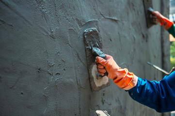 man is painting  wall with  trowel