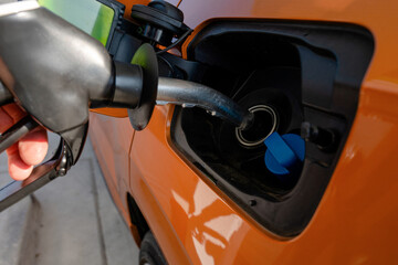 Obraz premium Person fills fuel tank at a gas station near a busy road in the afternoon