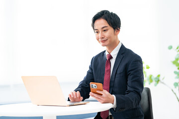 パソコンと携帯を見る男性