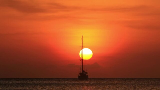 wide of ocean sunset with sun setting behind a sailboat in koh lanta , Thailand 4K 60fps