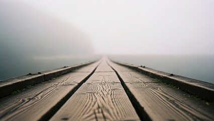 A wooden pier with leading lines disappearing into thick fog. Path representing a journey into the unknown future. Moody and mysterious background with copy space