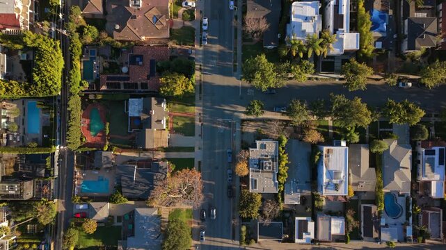 Cinematic top down view of Los Angeles California capturing residential street scene with detached homes, green trees, sidewalks and suburban atmosphere