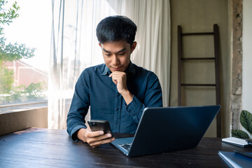 Businessman using laptop computer and smartphone in office. Happy man, entrepreneur, small business owner working online.