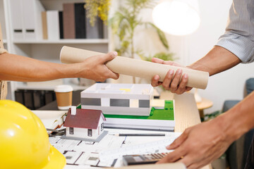 
Two people are working on a house plan design. They are using various tools, working with the...