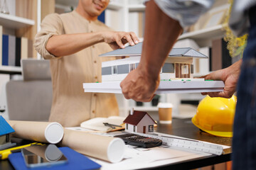 
Two people are working on a house plan design. They are using various tools, working with the...