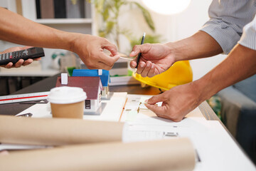 
Two people are working on a house plan design. They are using various tools, working with the...