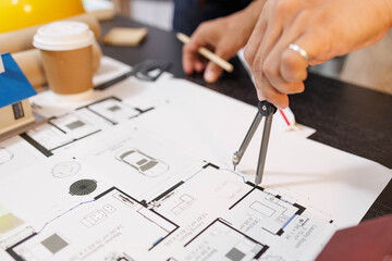 
Two people are working on a house plan design. They are using various tools, working with the...