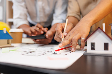 
Two people are working on a house plan design. They are using various tools, working with the...