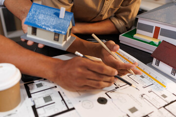 
Two people are working on a house plan design. They are using various tools, working with the...
