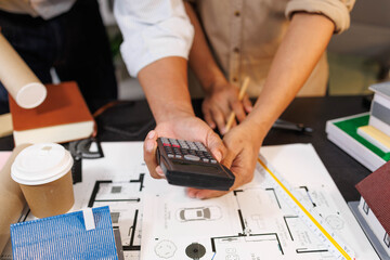 
Two people are working on a house plan design. They are using various tools, working with the...