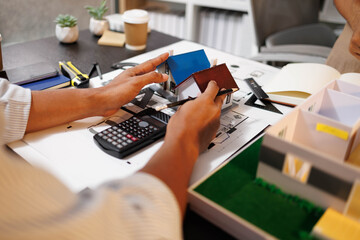 
Two people are working on a house plan design. They are using various tools, working with the...