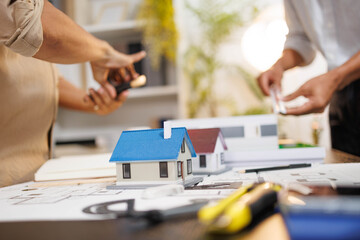 
Two people are working on a house plan design. They are using various tools, working with the...