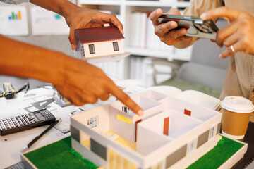 
Two people are working on a house plan design. They are using various tools, working with the...