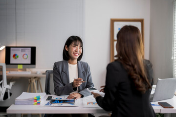 Asian businesswomen discussing financial data in office meeting