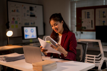 Asian businesswoman working late reviewing documents in office