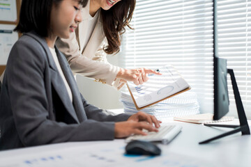 Businesswomen collaborating examining data charts on report in office