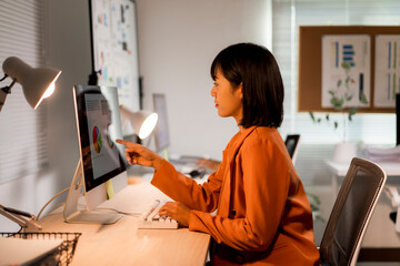 Asian businesswoman analyzing data and charting on computer in office