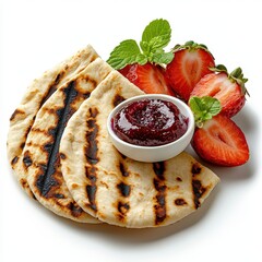 Grilled flatbread accompanied by fresh sliced strawberries, a small bowl of berry jam, and adorned with sprigs of vibrant green mint on a clean white surface.