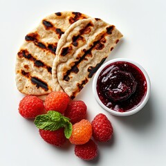 Grilled flatbread and vibrant raspberries are beautifully presented with homemade jam and fresh mint, offe a delicious and inviting culinary experience.