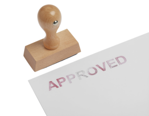 A wooden stamp with the word "APPROVED" printed in red ink on a white piece of paper.