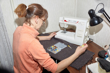 Woman sewing on a sewing machine at home. Concept of sewing craftsmanship
