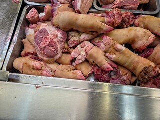 High-angle view of raw pork trotters and meat cuts displayed at a market.