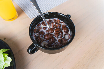 A bowl of chocolate cereal with milk on a table background. Delicious nutritious Breakfast for the child.