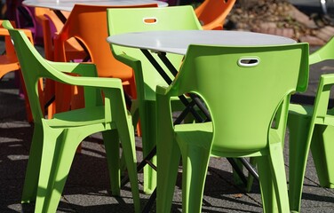 Bright green and orange plastic chairs at an outdoor cafe