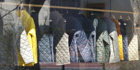 A colorful selection of padded winter vests behind a glass pane