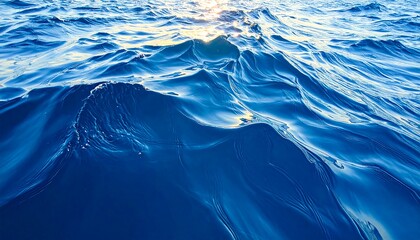 Close-up of undulating ocean water reflecting sunlight. Shades of blue dominate the imagery with shimmering highlights
