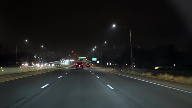 View of multiple cars driving on a highway at night with glowing headlights and taillights. Scene shows urban transportation, night traffic. US IL Chicago 25 Dec 2025