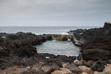 The natural pools of Garachico, Tenerife, Spain, are volcanic formations shaped by the 1706 eruption. Surrounded by rugged lava rock, they offer crystal-clear waters and a scenic coastal setting