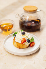 A creamy dessert adorned with strawberries and blueberries, paired with a steaming cup of tea