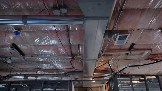 POV HVAC system under installation with exposed airducts, insulation, and metal framing inside a building. Ventilation, climate control construction work.
