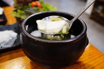 Authentic Korean radish water kimchi (Dongchimi) in a black stone bowl, close up shot
