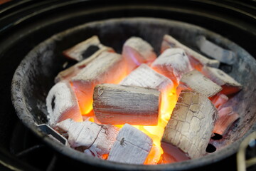 High quality Japanese Binchotan white charcoal glowing in a black metal grill