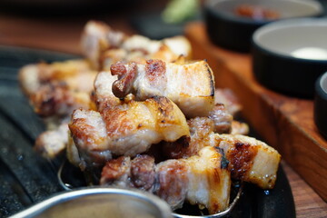 Sizzling Korean pork belly (samgyeopsal) grilling on a hot barbecue, close-up shot.
