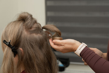 Fototapeta premium CloseUp of Hairstylist Using Curling Iron on Womans Hair