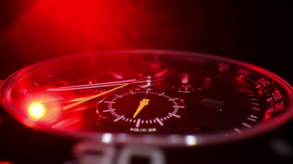 Macro close-up of a luxury chronograph watch illuminated by intense red light. The scene highlights precision timekeeping, a dramatic cinematic atmosphere.