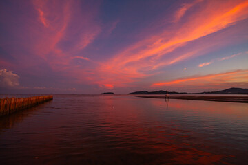 A radiant sunset paints the horizon in vivid tones of gold and purple. The still lake mirrors every color with perfect clarity, creating a dreamy balance of light, water, and silence at sunset.